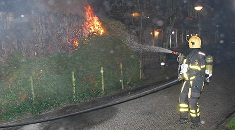 De coniferenhaag in brand aan de Beukenstraat.