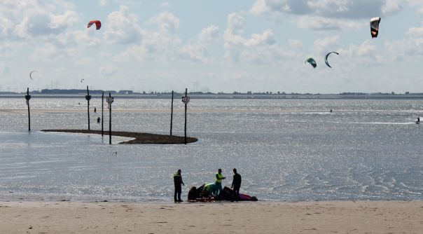 De kitesurfer is met vereende krachten van het strand gehaald.