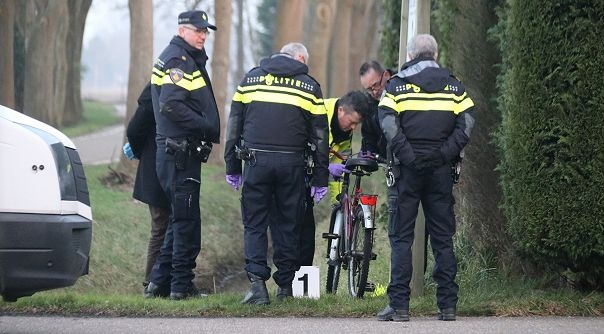 Politiemensen onderzoeken de fiets van het slachtoffer.