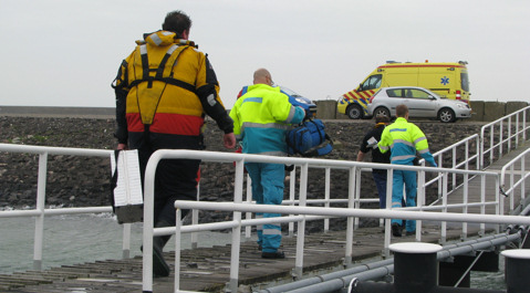 De visserman werd op de wal door het ambulanceteam geholpen.